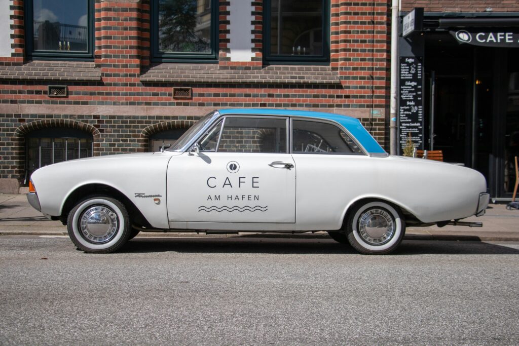 Vintage car parked in Hamburg near Cafe Am Hafen, capturing city life.